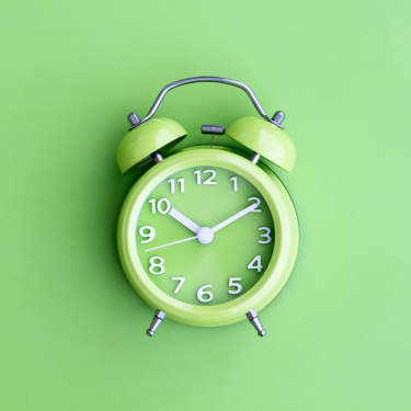 Green alarm clock on green background